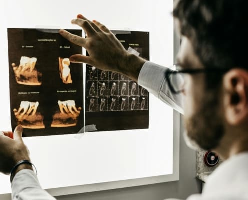 Dentist examining a dental X-ray on a screen in a clinical setting.